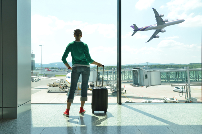 Chica con maleta y avión despegando